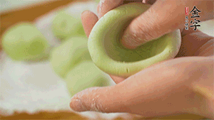 將均分的艾草面團(tuán)搓成圓，挖一個(gè)窩，放入餡心，再搓成圓。