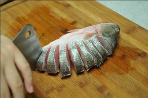 將鱸魚清洗干凈，從脊椎處切斷至腹部，腹部保留1cm左右不要切斷。