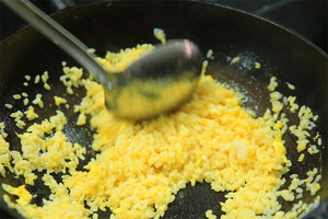 大火加熱炒鍋，再入油，燒到四至五成熱時倒入雞蛋液，在未凝結(jié)之前，加米飯煸炒，不停翻炒并用鍋鏟將成塊的米飯碾開、撥散。