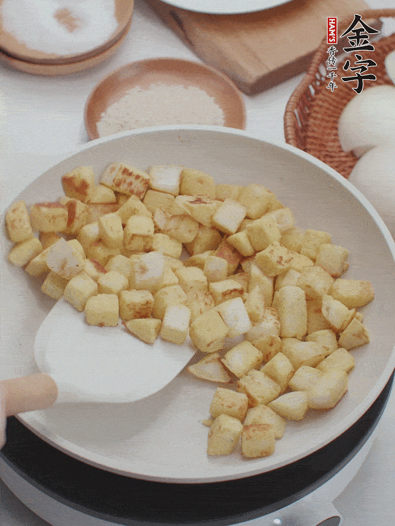 起鍋熱油，倒入饅頭丁，小火煎至蛋液凝固定型再翻面，饅頭丁部煎至金黃時(shí)盛起待用。