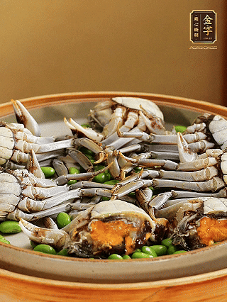 盤(pán)底鋪毛豆，依次放大閘蟹、咸肉， 淋一圈料酒、豉油。